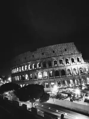 a large building is lit up at night at jacuzzi in front of the colosseum in Rome