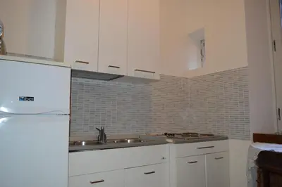 a kitchen with white cabinets and a sink and a refrigerator at Balcony Colosseum View in Rome