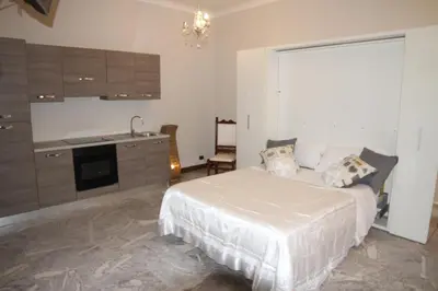 a bedroom with a white bed and a kitchen at View Colosseo From Jacuzzi in Rome