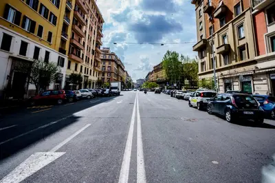 an empty city street with parked cars and buildings at Noemi's Rooms Guest House in Rome