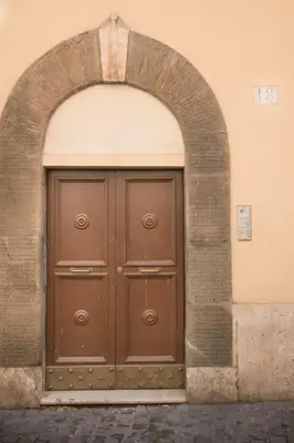 a large brown door in an archway on a building at St. Peter Manor in Rome