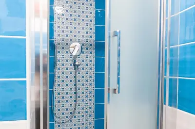 a shower in a bathroom with blue tiles at New Tiburtina in Rome