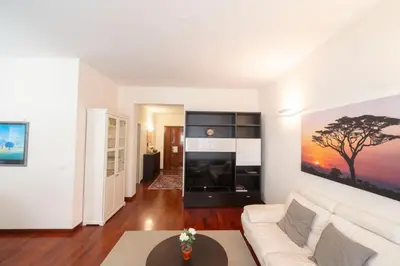 a living room with a white couch and a tree painting on the wall at St Peter new and lightsome apartment with balcony in Rome