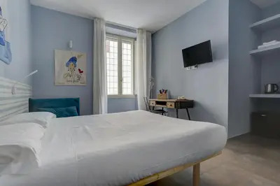 a bedroom with a large white bed and a television at CAPO D'AFRICA 30 - COLOSSEO in Rome