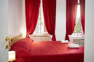 a red bed in a room with red curtains at Il Bonsai B&B in Rome