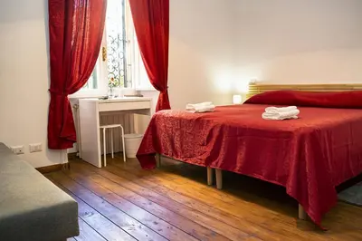 a bedroom with a bed with red sheets and a window at Il Bonsai B&B in Rome