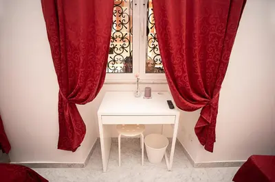 a room with a window with red curtains and a table at Il Bonsai B&B in Rome