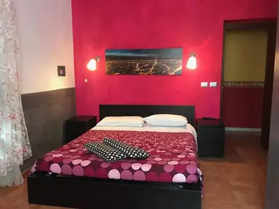 a bedroom with a bed with a red wall at La Casa di Elena in Rome
