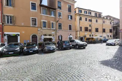 a cobblestone street with cars parked in front of buildings at Giuditta Suite 121 Trastevere Roma in Rome