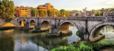 a stone bridge over a river in a city at Boutique Apartment Roma in Trastevere in Rome