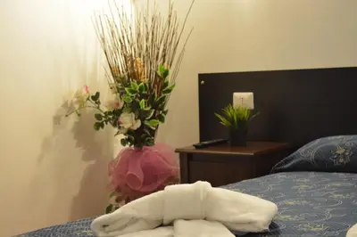 a towel on a bed next to a vase with flowers at Locanda Otello in Rome