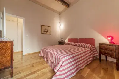 a bedroom with a bed with a striped bedspread and a dresser at Monti Stunning Apartment with Terrace in Rome