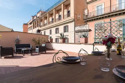 a wooden table with plates and flowers on a patio at Monti Stunning Apartment with Terrace in Rome