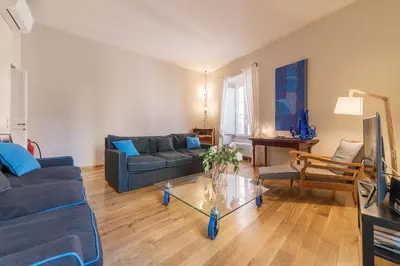 a living room with a blue couch and a glass table at Monti Stunning Apartment with Terrace in Rome