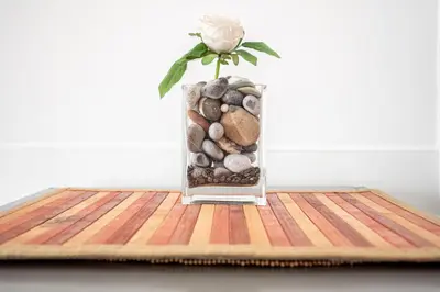 a vase filled with rocks and a rose on a table at Caracciolo Apartment - Metro San Giovanni in Rome