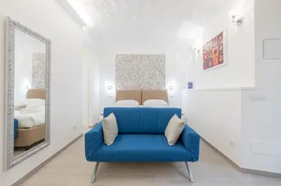a blue chair in a white room with a mirror at Dolce Vita New Studio in Rome