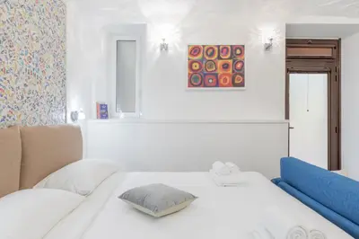 a white bedroom with a bed and a painting at Dolce Vita New Studio in Rome