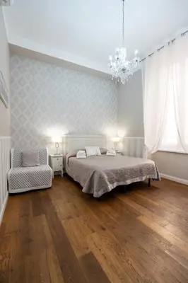 a bedroom with a bed and a chair and a chandelier at Casa De Rose in Rome