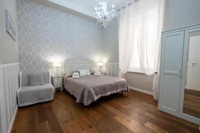 a bedroom with a bed and a chair and a chandelier at Casa De Rose in Rome