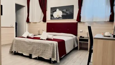 a bedroom with a bed with a red and white blanket at Hotel Balilla in Rome