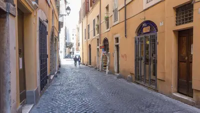 a man walking down a cobblestone alley with buildings at Rental in Rome Falegnami in Rome