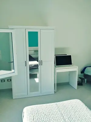 a white bedroom with a bed and a desk with a laptop at Roma TouristHome via palestro 56 in Rome