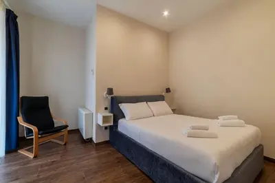 a bedroom with a large bed and a chair at GuestHost - Sallustiano Apartments in Rome