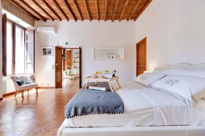 a white bedroom with a large bed and a table at Arenula Luxury Apartment in Rome