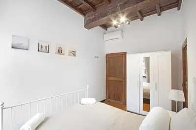 a white bedroom with a bed and a wooden ceiling at Arenula Luxury Apartment in Rome