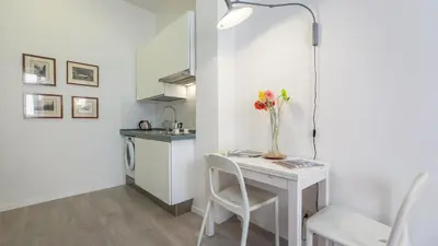 a small white kitchen with a table and a vase of flowers at Rental in Rome Beato Angelico in Rome