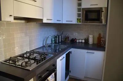 a kitchen with a stove and a sink and white cabinets at La Casetta del Flaminio a Roma Centro in Rome