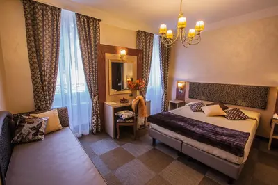 a bedroom with a bed and a chair and a mirror at Hotel Romano in Rome