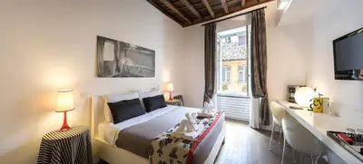 a bedroom with a bed and a desk and a window at Relais Fori Imperiali in Rome