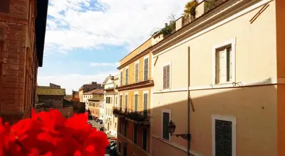 a view of a city street with buildings and red flowers at Torre Tolomei Trastevere in Rome