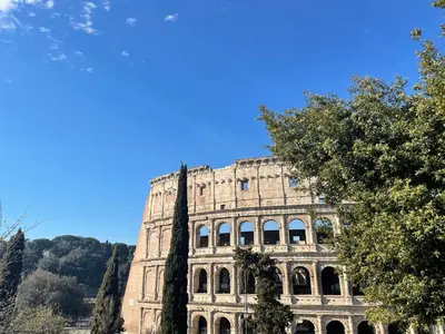 an old building with a blue sky in the background at Colosseo Gardens - My Extra Home in Rome