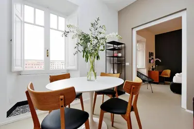 a dining room with a table and chairs and a vase with flowers at YCH-Bright Penthouse near COLOSSEUM in Rome