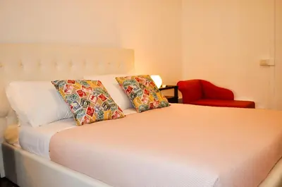 a bedroom with a bed with two pillows and a red chair at Trastevere Boulevard in Rome