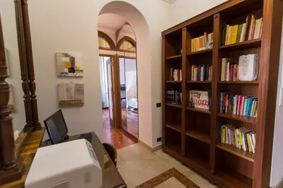 an office with a desk and book shelves with books at Monia Coliseum Apartment in Rome