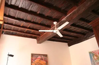 a ceiling fan in a room with wooden ceilings at Portico d'Ottavia, the ancient Rome in Rome