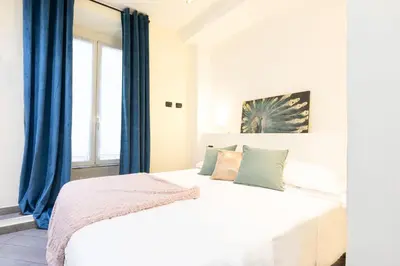 a bedroom with a white bed with blue curtains at Cesar Vatican Rooms in Rome