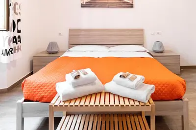 an orange bed with two towels on a bench at Sannio Apartment - near Metro San Giovanni by RHR in Rome