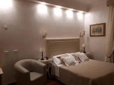 a white bedroom with a bed and a chair at Locanda Navona in Rome