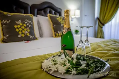 a bottle of champagne and a plate of flowers on a bed at Chic & Town Luxury Rooms Piazza di Spagna in Rome