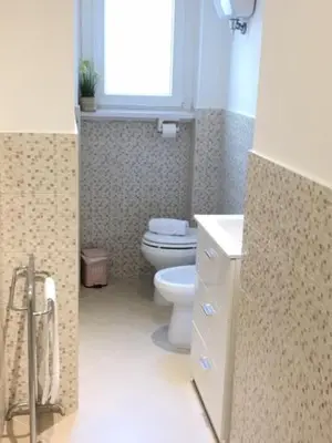 a bathroom with a toilet and a sink and a window at RELAX INN VATICAN in Rome