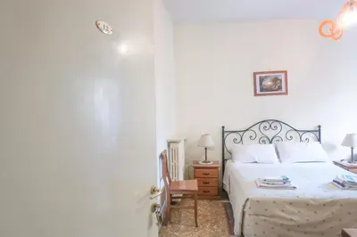 a white bedroom with a bed and a chair at The Condottieri in Rome