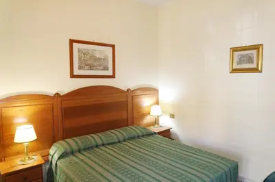 a bedroom with a bed with a green bedspread and two lamps at The Condottieri in Rome