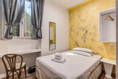 two beds in a room with a yellow wall at Hotel Santa Prassede in Rome