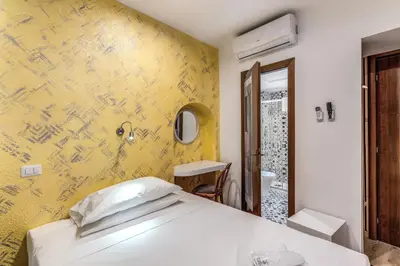 a bedroom with a white bed and a yellow wall at Hotel Santa Prassede in Rome