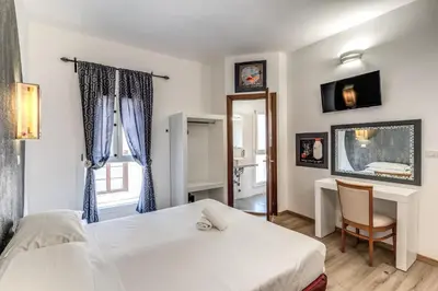 a bedroom with a bed and a desk and a window at Hotel Santa Prassede in Rome
