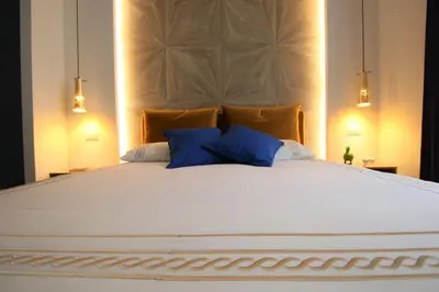 a large white bed with two blue pillows on it at My Love Suite in Rome